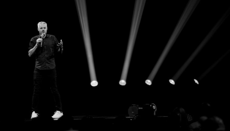 Speaker on stage with beams of light behind